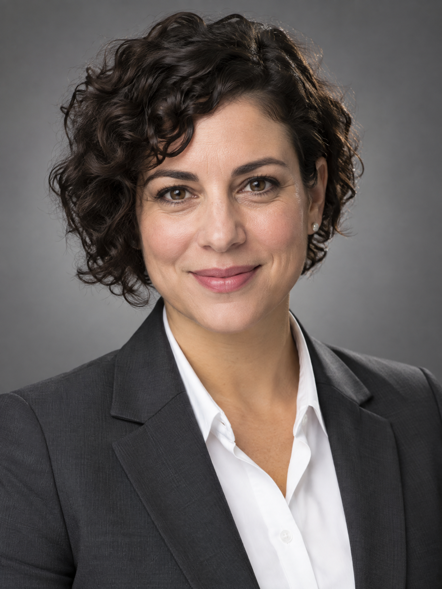 Professional headshot of a woman with short curly hair in a blazer